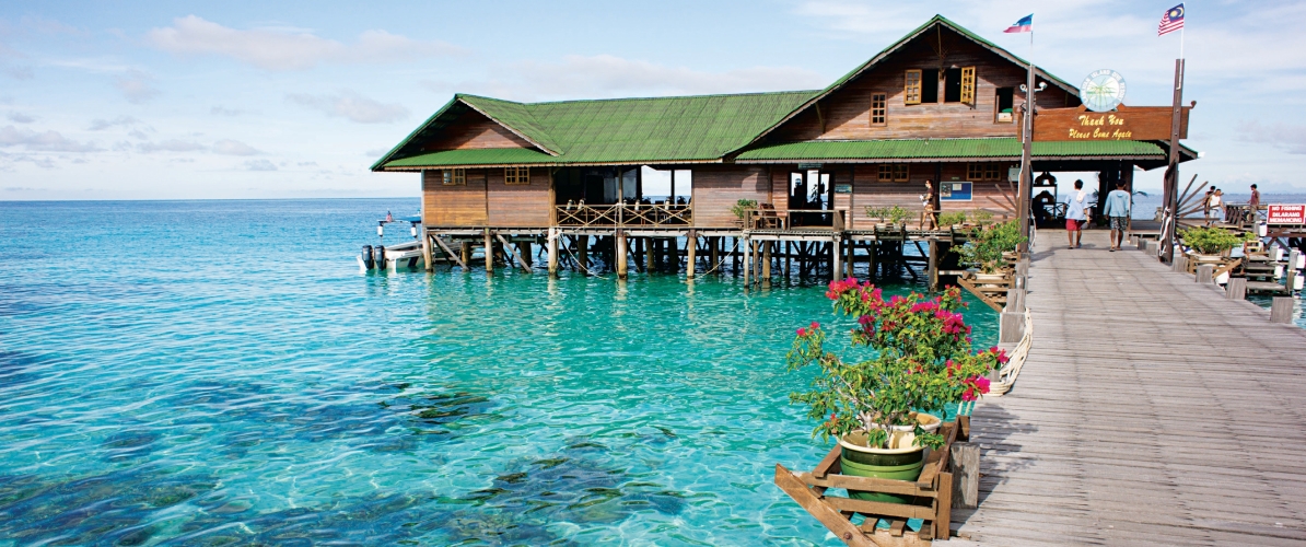 A stunning view of a wooden jetty leading to a rustic overwater structure at Pulau Tiga